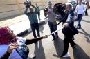 A supporter of the head of Egypt's military, Abdel-Fattah el-Sissi, left, wearing a t-shirt with his image, scuffles with a Muslim Brotherhood lawyer, Ahmed Kamel, after she struck him outside a makeshift courtroom at the national police academy, in an eastern suburb of Cairo, Egypt, Saturday, Feb. 1, 2014. The trial of Egypt's ousted president, Mohammed Morsi and 14 others also accused of inciting the killing of protesters resumed on Saturday. The trial is one of four Morsi and top leaders of his Muslim Brotherhood face with the charges levelled against them mostly carrying the death penalty. (AP Photo/Ahmed Omar)