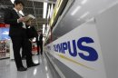 A man is seen next to an Olympus logo at an electronics shop in Tokyo