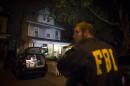 An FBI agent stands guard as evidence sits in the trunk of a vehicle at the Brooklyn residence of Rabbi Mendel Epstein during an investigation, early Thursday, Oct. 10, 2013, in New York. Several defendants, including Epstein and another rabbi, were arrested in an overnight sting in New York and New Jersey and accused by the FBI of plotting to kidnap and beat a man to force him to grant a religious divorce. (AP Photo/John Minchillo)