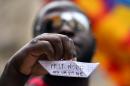 An asylum seekers holds a paper boat that says in Italian, "Too many deaths, it is not good" during a demonstration in front of the Italian parliament in Rome, on April 23, 2015