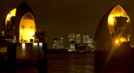 FILE - The financial center of Canary Wharf just outside the boundary of the City of London is seen through the Thames Barrier at night on Friday, Dec. 28, 2012. The low-lying city has long been vulnerable to flooding - particularly when powerful storms send seawater racing up the River Thames. But the 570-yard-long (half-a-kilometer-long) barrier, composed of 10 massive steel gates, each five stories high when raised against high water, has been in operation since 1982. (AP Photo/Alastair Grant, File)