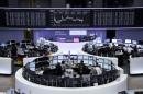 Traders are pictured at their desks in front of DAX board at the Frankfurt stock exchange