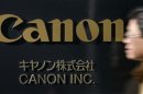 A man walks past a Canon Inc. sign at the company's headquarters in Tokyo