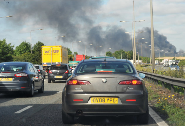 Smoke from a burning Sony distribution center reportedly set alight by rioters, rises above London's major M25 motorway near Enfield, north London, Tuesday Aug. 9 2011.  A wave of violence and looting