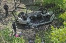 Police investigate the destroyed van that plunged over the Bronx River Parkway, Sunday April 29, 2012, in New York. Authorities say the out-of-control van plunged off a roadway near the Bronx Zoo, killing seven people, including three children. (AP Photo/ Louis Lanzano)