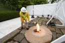 This handout photo provided by Arlington National Cemetery, taken April 29, 2013, shows Randy Barton, an Arlington National Cemetery engineering technician, lighting a torch from the John F. Kennedy Eternal Flame at the cemetery in Arlington, Va. The torch was used to transfer the flame to a temporary burner while the permanent flame undergoes repair and upgrade work to install new burners, a new igniter as well as new gas and air lines. The eternal flame at the gravesite of former President John F. Kennedy is undergoing repairs at the cemetery. Before the repairs began, workers used a torch to carry the flame and pass it to a temporary burner that will be visible to tourists at the site while work is underway. Cemetery officials say the work will take about three weeks and should be completed by late May, when the flame will be passed back to the original site. A temporary flame was used from the time of Kennedy's November 1963 funeral until the permanent flame was established in 1967. Officials said repairs are needed after more than four decades of use and will include new gas lines and more efficient burners. (AP Photo/Patrick Bloodgood, US Army, Arlington National Cemerery)
