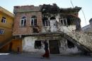 A woman walks past a building which was damaged during the security operations and clashes between Turkish security forces and Kurdish militants, in the southeastern town of Silvan in Diyarbakir province, Turkey