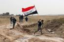 File - This Monday, March 30, 2015 file photo shows a member of the Iraqi security forces running to plant the national flag as they surround Tikrit during clashes to regain the city from Islamic State militants, 80 miles (130 kilometers) north of Baghdad, Iraq. (AP Photo/Khalid Mohammed, File)