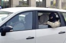 An unidentified man with his head covered, believed to be Abdelkader Merah or his companion, sits between masked police officers as they head to the French police's anti-terrorist headquarters in Levallois-Perret, outside Paris, Saturday, March 24, 2012. Merah's brother, Mohamed Merah is blamed for a series of deadly shootings which have shocked France and upended the country's presidential race. Merah, who claimed allegiance to al-Qaida, died in a hail of gunfire Thursday after a dramatic 32-hour-long standoff with law enforcement. (AP Photo/Christophe Ena, Pool)