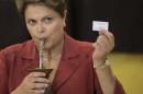 Brazil's President and Workers Party presidential candidate Dilma Rousseff, shows her electronic voting receipt that confirms she voted in the presidential runoff election as she drinks mate, an herbal tea, in Porto Alegre, Brazil, Sunday, Oct. 26, 2014. Rousseff is leading opposition contender Aecio Neves 51-to-49 percent with 95 percent of the vote counted. Still, there are too many uncounted votes for a winner to be declared. That's according to the official count Sunday night from the nation's top electoral court. (AP Photo/Felipe Dana)