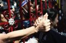 An anti-government protester touches hand of police officer through main gate of Thai Police Headquarters in Bangkok