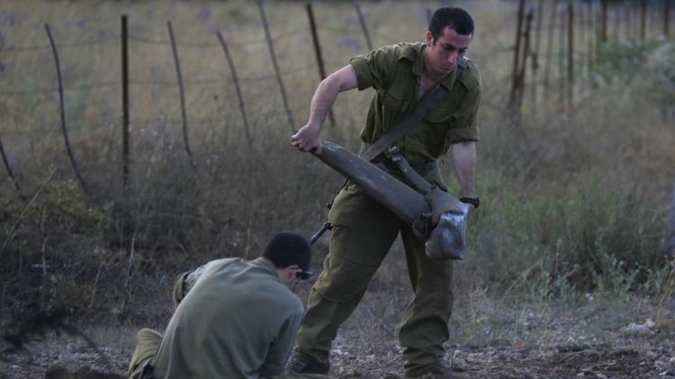 Israeli soldiers collect the remains of a rocket reported launched from Syria into the Israeli-annexed Golan Heights on July 14, 2014