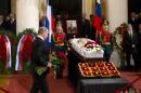 Russian President Vladimir Putin, left, walks with flowers during a civil funeral for former Russian Prime Minister Yevgeny Primakov, in Moscow's House of the Unions, Russia, Monday, June 29, 2015. Primakov, whose career included journalism, diplomacy and spycraft, has died at age 85. (AP Photo/Alexander Zemlianichenko)