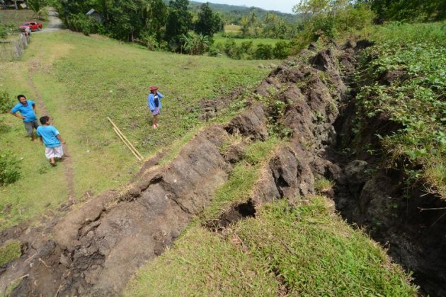 This photo taken on October 22, 2013 shows residents standing next to a huge crack creating a rock wall in the village of Anonang, Inabanga town, Bohol province brought about by the 7.2-magnitude quake which hit the province October 15