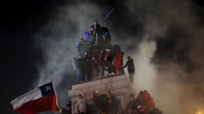 Chilean fans climb onto the monument of national hero Manuel Baqueano during celebrations after Chile&#39;s victory over Uruguay in their Copa America 2015 quarter-finals soccer match in Santiago