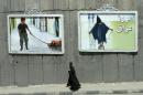 An Iranian couple walk past mural paintings depicting scenes from the torture of Iraqi prisoners by US soldiers at the Abu Ghraib prison near Baghdad, in Tehran, on June 1, 2004