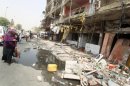 An Iraqi woman walks past destroyed shops on the ground floor of a building in the Karrada area of Baghdad
