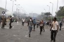 Supporters of President Mursi run from tear gas thrown by police during clashes in Nasr city area