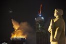 A firefighting helicopter drops water to extinguish fire atop an under-construction skyscraper, planned to be Europe's tallest building, in Moscow, Russia, Monday, April 2, 2012, with the statue of a woman-defender of Moscow in WWII, foreground right. Orange flames were leaping about 250 meters (880 feet) Monday, visible in the night sky to much of the city. No injuries have been reported at the fire in the eastern tower of the Federation Tower complex, part of a massive development along the Moscow River about 2.5 kilometers (1.5 miles) west of the Kremlin. The tower, when completed, is to be 360 meters (1150 feet) tall. (AP Photo/Alexander Zemlianichenko)