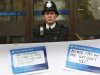 A police officer stands on duty as protestors from the Move Your Money group stick up posters on a branch of Barclays Bank in Westminster central London