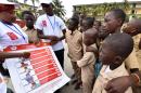 Volunteers wearing t-shirts of the United Nations Development Programme show a placard to raise awareness about the symptoms of the Ebola virus to students in Abidjan, on September 15, 2014