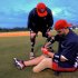 In this Friday, Jan. 13, 2012, photo, Wounded Warrior Amputee Softball Team member Joshua Wege, left, assists teammate Daniel Lasko as he uses a wrench to repair his prosthetic leg before an exhibition game against the Fellowship of Christian Athletes, which features former Olympic softball team members Jennie Finch and Dot Richardson, in Plant City, Fla. (AP Photo/Brian Blanco)