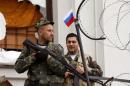 Armed pro-Russian activists stand guard at the entrance of the seized regional government headquarters in Luhansk