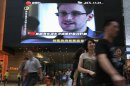 A TV screen shows a news report of Edward Snowden, a former CIA employee who leaked top-secret documents about sweeping U.S. surveillance programs, at a shopping mall in Hong Kong Sunday, June 23, 2013. The former National Security Agency contractor wanted by the United States for revealing two highly classified surveillance programs has been allowed to leave for a "third country" because a U.S. extradition request did not fully comply with Hong Kong law, the territory's government said Sunday. (AP Photo/Vincent Yu)