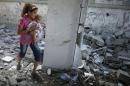 Palestinian girl holding her sister walks through debris near remains of a mosque, which witnesses said was hit by an Israeli air strike, in Beit Hanoun in the northern Gaza Strip