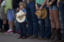 A young boy holds his hat as he and others stand for the national anthem before the start of the Prescott Frontier Days Rodeo, Wednesday, July 3, 2013 in Prescott, Ariz. A mile-high city about 90 miles northwest of Phoenix, Prescott remains a modern-day outpost of the pioneer spirit. It's that spirit that will guide officials as they navigate the days ahead and figure out how to honor the elite Hotshot firefighters who died in a nearby wind-driven wildfire that is still burning. (AP Photo/Julie Jacobson)