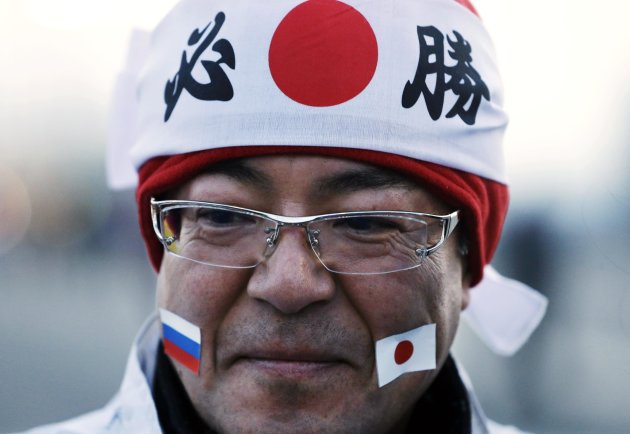 A fan wears stickers of a Russian, left, and Japanese flag while visiting Olympic Park at the 2014 Winter Olympics. (AP Photo/Darron Cummings)