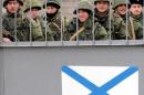 Russian naval soldiers stand behind the gates of their base as they guard the Orsk Russian landing ship anchored in the Ukraine's Black Sea port of Sevastopol on March 2, 2014, with a Russian naval flag painted on the gates