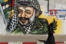 Palestinian woman walks past a mural depicting late leader Arafat in Gaza