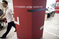 In this Aug. 1, 2011 photo, a worker walks inside an office of Beijing Goldlink Go-Abroad Consulting Co., an immigration consulting firm assisting Chinese to immigrate to Canada and the United States, in Beijing. Among the 20,000 Chinese with at least 100 million yuan ($15 million) in individual investment assets, 27 percent have already emigrated and 47 percent are considering it, according to a report by China Merchants Bank and U.S. consultants Bain & Co. published in April. (AP Photo/Alexander F. Yuan)