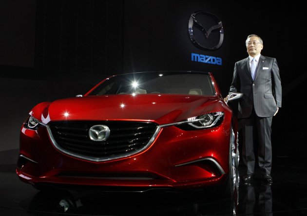 Mazda Motor Corp Chief Executive Yamanouchi poses with the company's new concept car at the 42nd Tokyo Motor Show in Tokyo