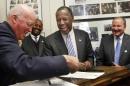 Republican presidential candidate, Dr, Ben Carson, center, laughs with New Hampshire Secretary of State Bill Gardner after signing filing papers to be on the nation's earliest presidential primary ballot, Friday, Nov. 20, 2015, in Concord,N.H. (AP Photo/Jim Cole)