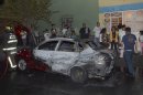 People stand in front of a partially burned vehicle after gunmen shot and killed an as of yet undetermined number of people in the Tepito neighborhood in Mexico City, Thursday June 6, 2013. (AP Photo)