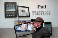 FILE - In this file photo taken on Jan. 26, 2011, a man stands near Apple's iPad advertisement in Shanghai, China. The official said Monday, Feb. 13, 2012, that investigators in Shijiazhuang, southwest of Beijing, started seizing iPads last week at the request of a company that filed a complaint with the government accusing Apple Inc. of violating its rights to the iPad name. (AP Photo/Eugene Hoshiko, File)