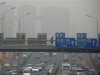 A pedestrian walks across a bridge above a main road on a day with high air pollution in Beijing