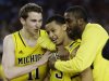 Michigan's Nik Stauskas (11), Trey Burke (3) and Corey Person celebrate after beating Kansas  87-85 in overtime of a regional semifinal game in the NCAA college basketball tournament, Friday, March 29, 2013, in Arlington, Texas. (AP Photo/David J. Phillip)