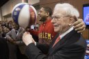 Berkshire Hathaway Chairman and CEO Warren Buffett, right, is watched by Detroit Lions defensive tackle Ndamukong Suh, left, as he is assisted by Harlem Globetrotter Chris 