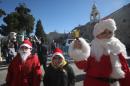 Palestinian children dressed up as Santa Claus pose at Manger Square outside the Church of the Nativity in Bethlehem on December 24, 2013