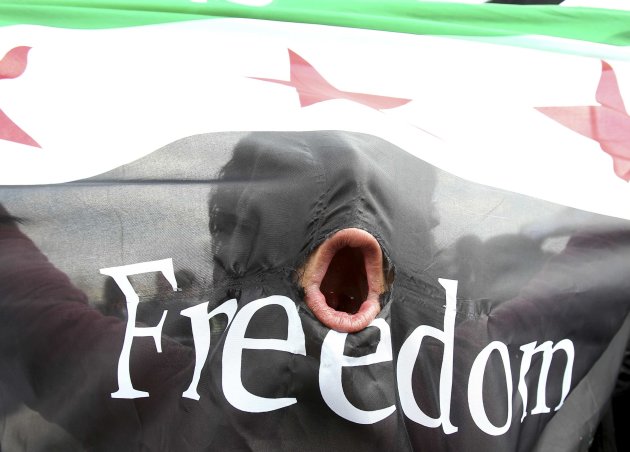 A protester stands behind a Syrian Republic flag as Syrian refugees and local residents take part in a demonstration against Syria's President Bashar Al-Assad, after Friday prayers outside the Syrian 