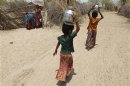 Village girls carry metal pitchers filled with water supplied by the government in Gujarat