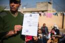 An Iraqi soldier from the Iraqi army 9th armoured division holds a death certificate issued by the Islamic State next to a base adjacent to the Al-Intissar neighbourhood of Mosul, on November 7, 2016