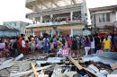 Residents watch others throw items out from a warehouse after super typhoon Haiyan hit Guiuan