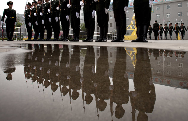 Soldiers of the Chinese People's Liberation Army's honor guard battalions are reflected in a puddle of water during their daily training demonstrated to visiting media persons at their military base i