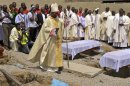 Clergymen gather around the coffins of the victims of the Christmas day bombing at St Theresa Catholic Church Madalla, during a mass funeral for the victims, outside Nigeria's capital Abuja