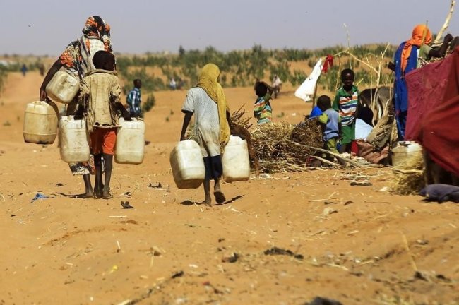 People walk to fill water containers at the Zamzam IDP camp for Internally Displaced Persons (IDP), near El Fasher in North Darfur February 4, 2015. R...