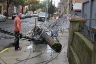 Two men examine a toppled telephone pole in the Queens borough of New York, Sunday, Aug. 28, 2011. Although downgraded from hurricane status, Tropical Storm Irene unleashed furious wind and rain on New York, flooding streets, downing trees and power lines. (AP Photo/Brian Scanlon)